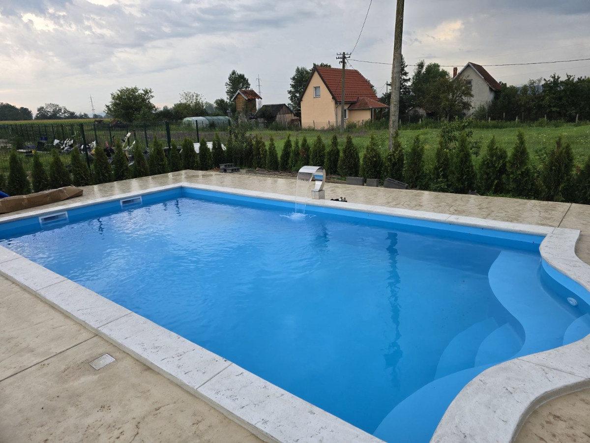 zavrsen plavi bazen u dvoristu sa pogledom na selo